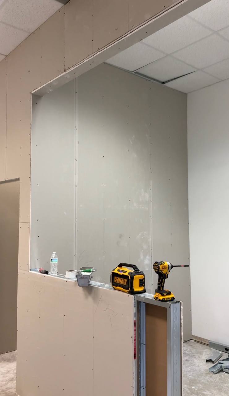 Commercial build-out — drywall hung, DeWalt tools on ledge
