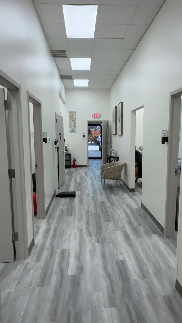 Finished commercial hallway with gray flooring, white walls, and office doors