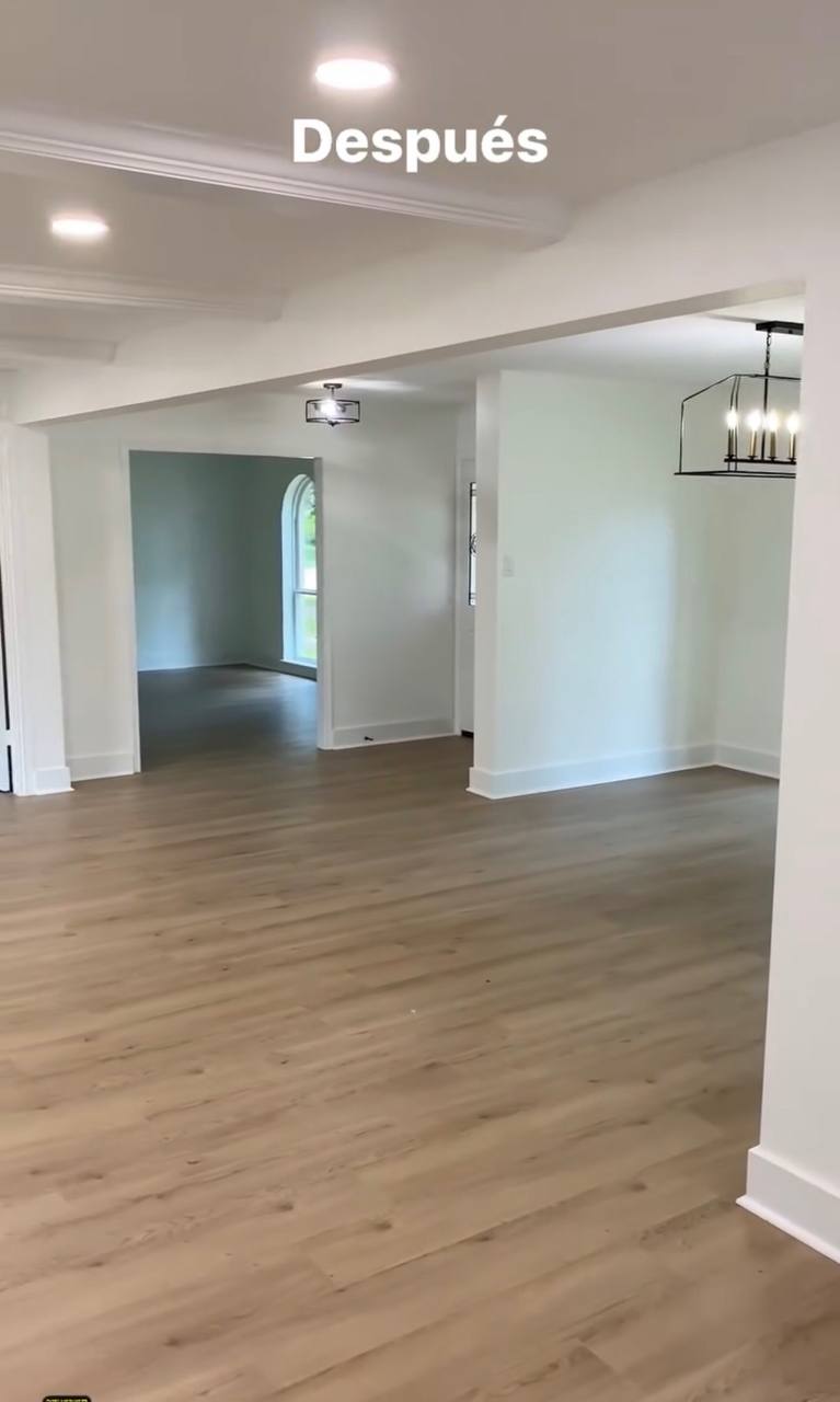 Finished open floor plan — warm hardwood LVP, crown molding, pendant chandelier